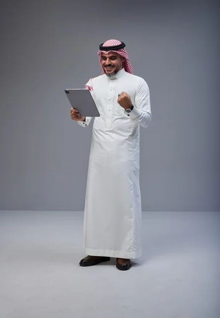 Saudi Man in Traditional Thobe with Tablet Celebrating in Studio