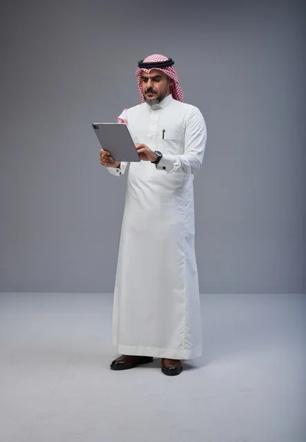 رجل سعودي بالزي التقليدي يستخدم جهاز لوحي في الاستوديو