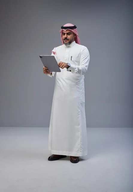 رجل سعودي بالزي التقليدي يستخدم جهاز لوحي في الاستوديو