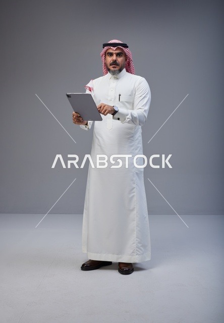Saudi Man in Traditional Thobe Using Digital Tablet