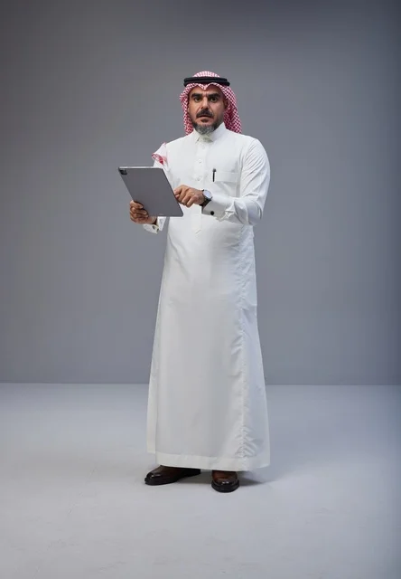 رجل سعودي بالزي التقليدي يستخدم جهاز لوحي