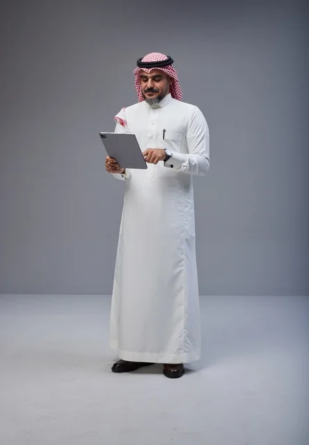 رجل سعودي بالزي التقليدي يستخدم جهاز لوحي