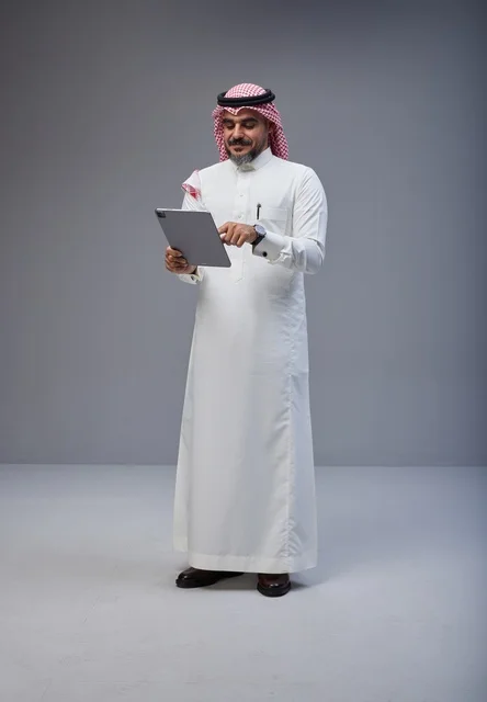 Saudi Man in Traditional Dress Using Tablet in Studio