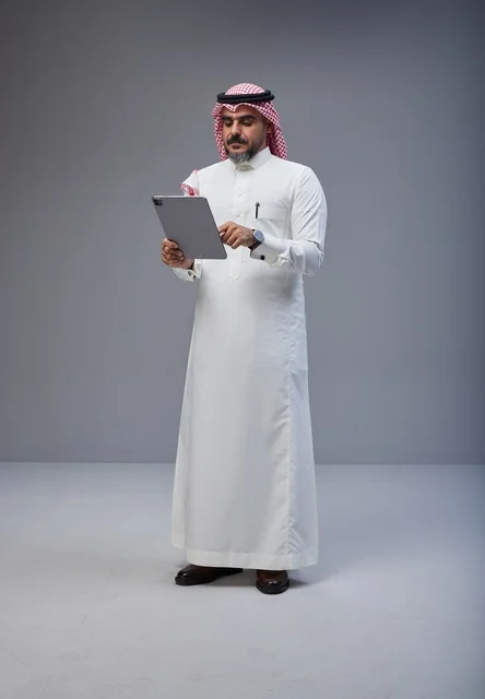 رجل سعودي بالزي التقليدي يستخدم جهاز لوحي