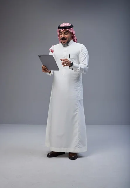 رجل سعودي بالزي التقليدي يستخدم جهاز لوحي