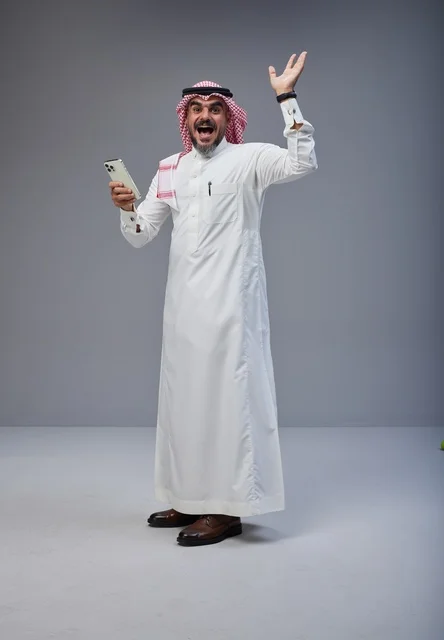 Excited Saudi Man in Thobe Using Smartphone
