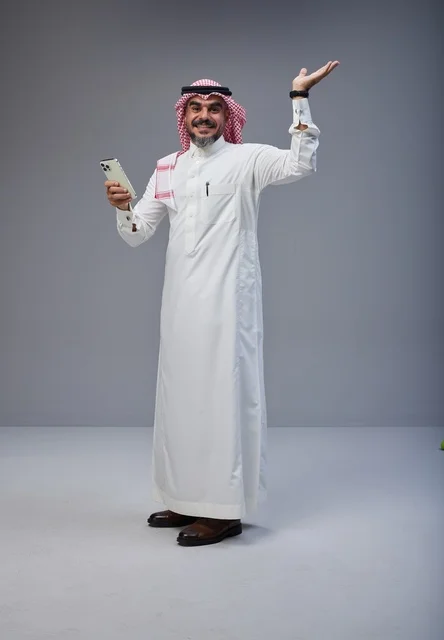 رجل سعودي بالزي التقليدي يستخدم الهاتف في الاستوديو