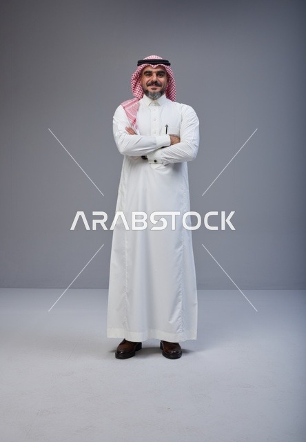 رجل سعودي بالزي التقليدي يقف بوضعية مكتف اليدين