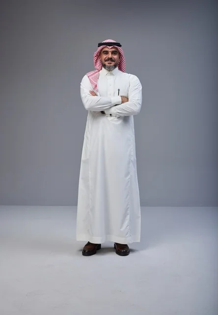 رجل سعودي بالزي التقليدي يقف بوضعية مكتف اليدين
