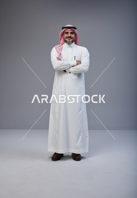 رجل سعودي بالزي التقليدي يقف بثقة في الاستوديو