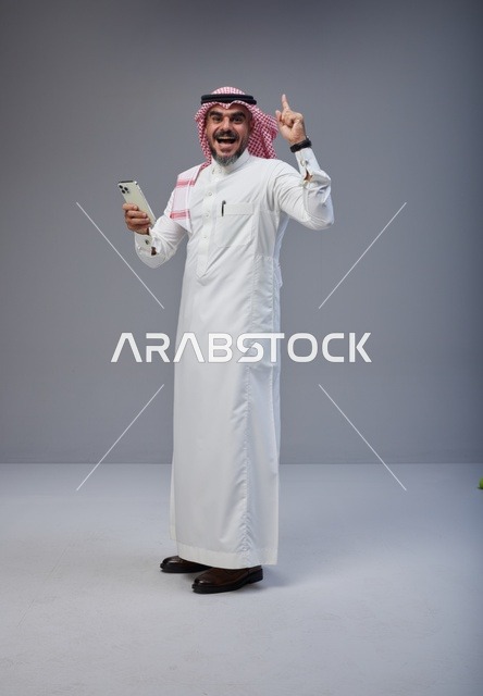 Saudi Man in Thobe Holding Smartphone Pointing Up
