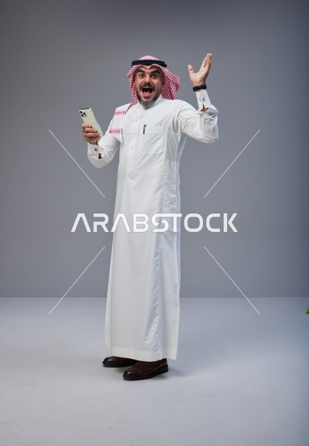 رجل سعودي بالزي التقليدي يستخدم الهاتف أثناء المشي