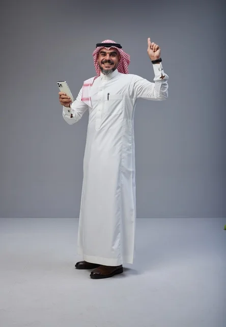 Saudi Man in Thobe Pointing Up with Smartphone