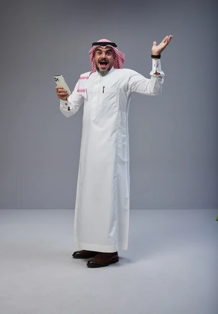 Saudi Man in Traditional Thobe Reacting to Smartphone