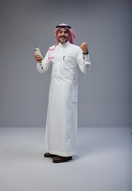Saudi Man in Traditional Dress Celebrating with Smartphone