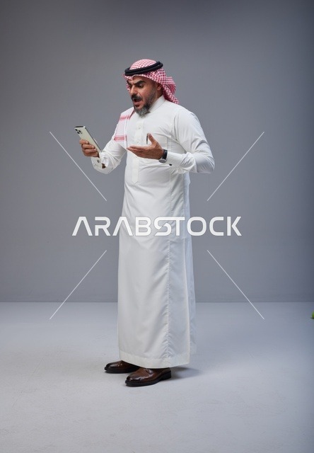 رجل سعودي بتعبير مندهش يستخدم الهاتف في الاستوديو