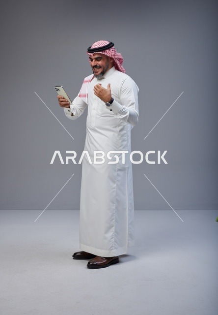 Saudi Man in Traditional Thobe Using Smartphone