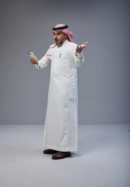 رجل سعودي متفاجئ يستخدم الهاتف الذكي في الاستوديو
