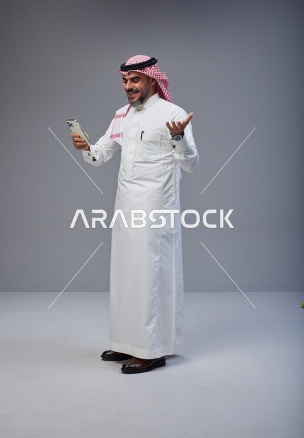 Saudi Man in Traditional Thobe Using Smartphone