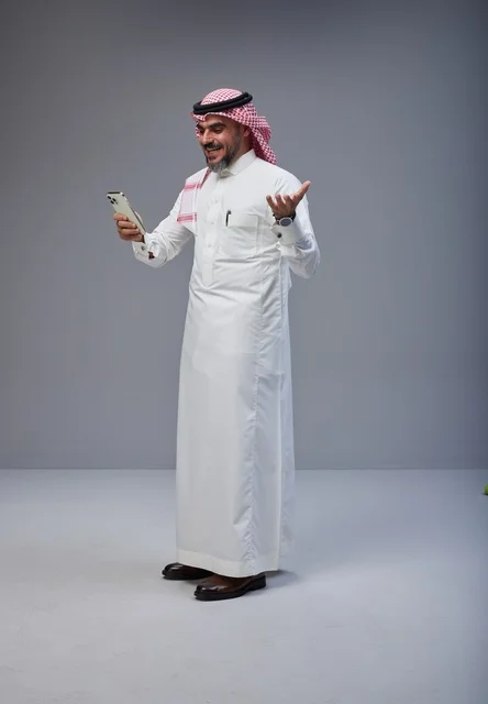 Saudi Man in Traditional Thobe Using Smartphone
