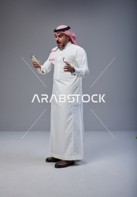 Shocked Saudi Man Looking at Smartphone in Studio