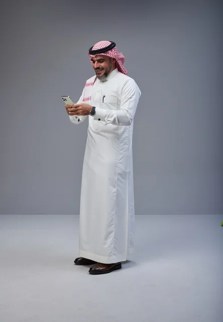 Saudi Man in Traditional Thobe Using Smartphone