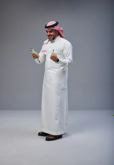 Saudi Man in Traditional Dress Using Smartphone