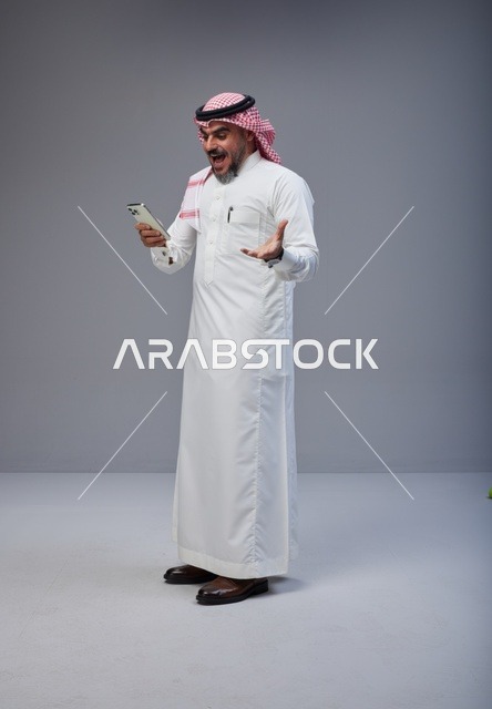 Saudi Man in Traditional Thobe Reacting to Smartphone