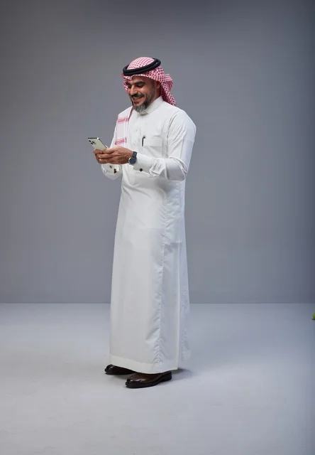 Saudi Man in Traditional Thobe Using Smartphone in Studio