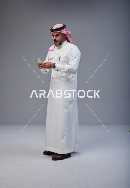 Saudi Man in Traditional Thobe Using Smartphone