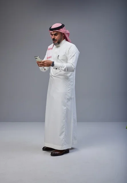 Saudi Man in Traditional Thobe Using Smartphone