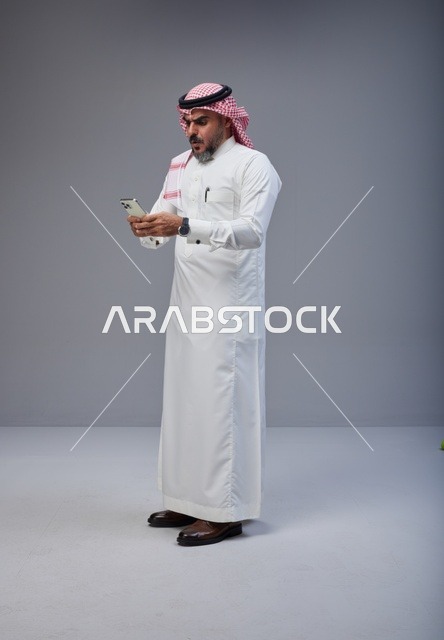 Saudi Man in Traditional Thobe Using Smartphone