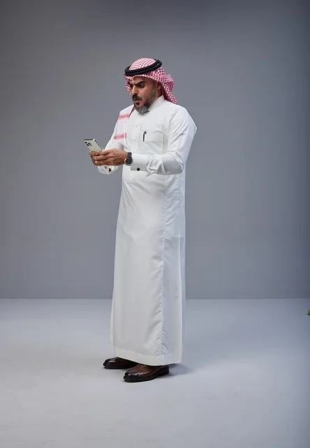 Saudi Man in Traditional Thobe Using Smartphone