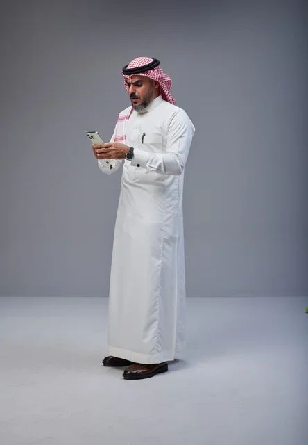 Saudi Man in Traditional Thobe Using Smartphone