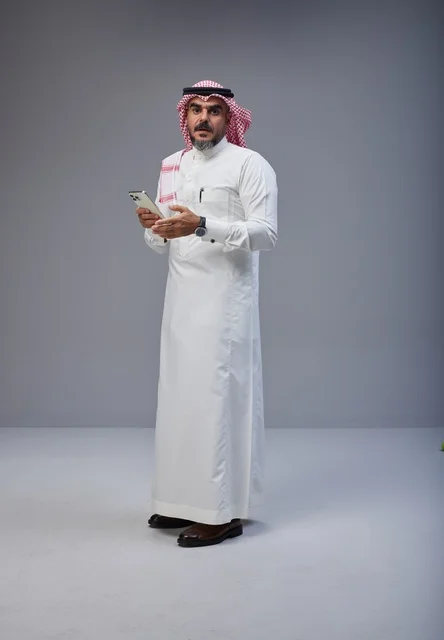 رجل سعودي بالزي التقليدي يستخدم الهاتف الذكي
