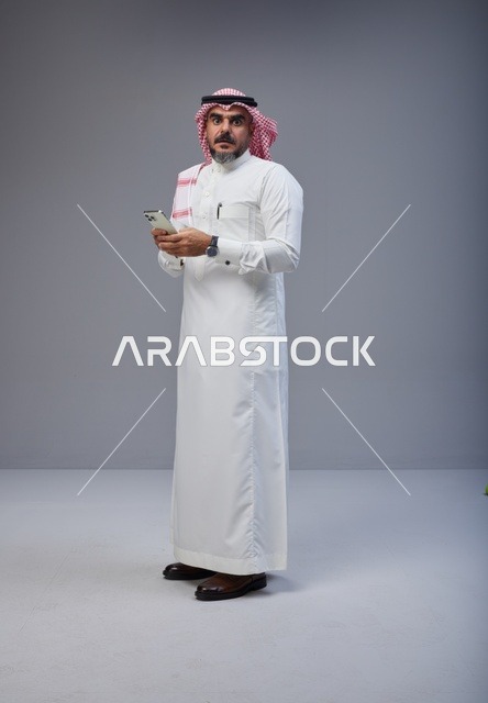 Saudi Man in Traditional Thobe Using Smartphone