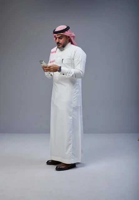 Saudi Man in Traditional Thobe Using Smartphone