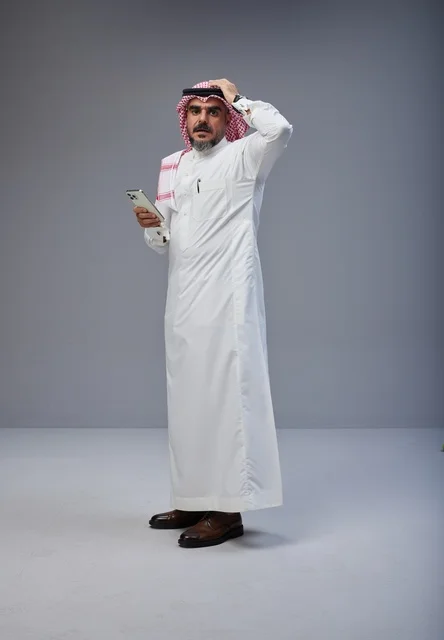 رجل سعودي بالزي التقليدي يمسك هاتف ذكي