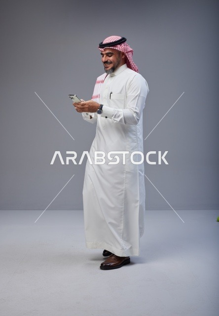 Saudi Man in Thobe Using Smartphone While Walking