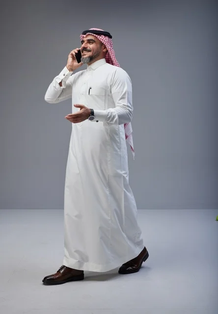 Saudi Man in Traditional Dress Talking on Smartphone Walking