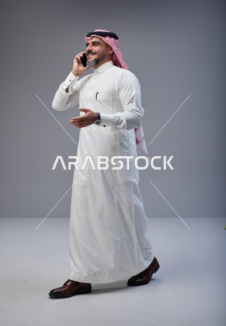 رجل سعودي بالزي التقليدي يتحدث عبر الهاتف الذكي