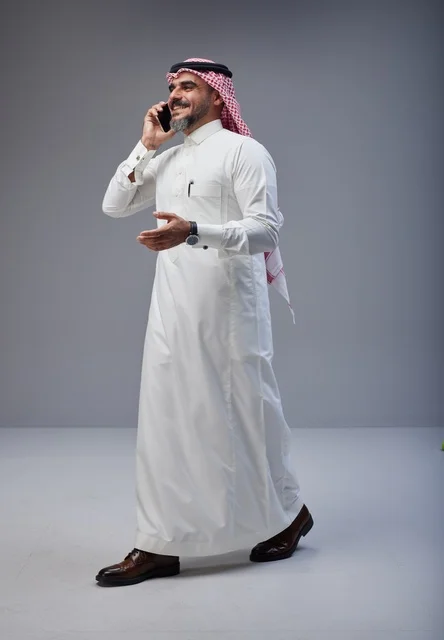 رجل سعودي بالزي التقليدي يتحدث عبر الهاتف الذكي