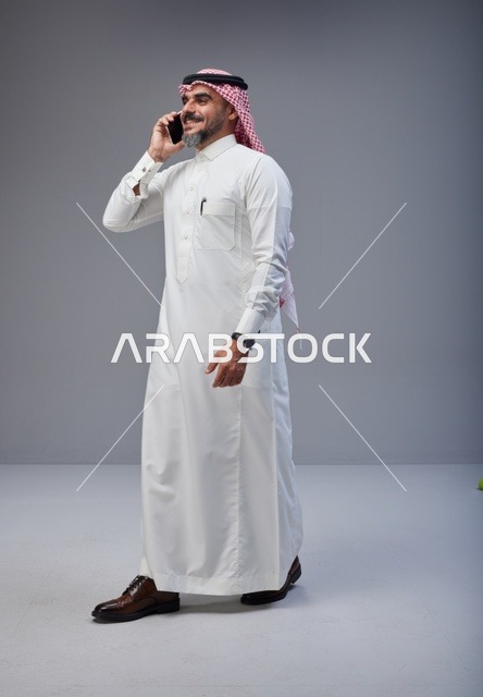 Saudi Man in Traditional Thobe Talking on Smartphone