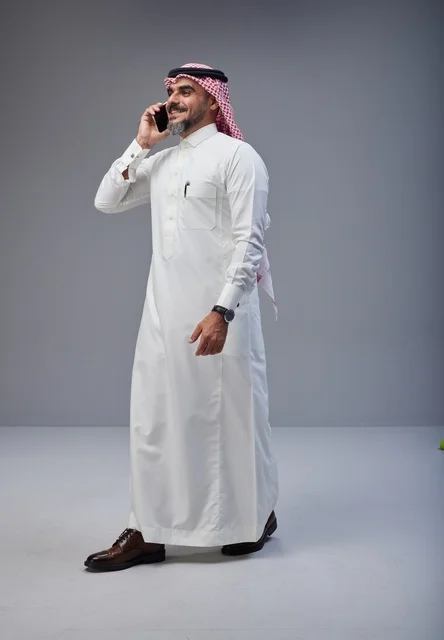 Saudi Man in Traditional Thobe Talking on Smartphone
