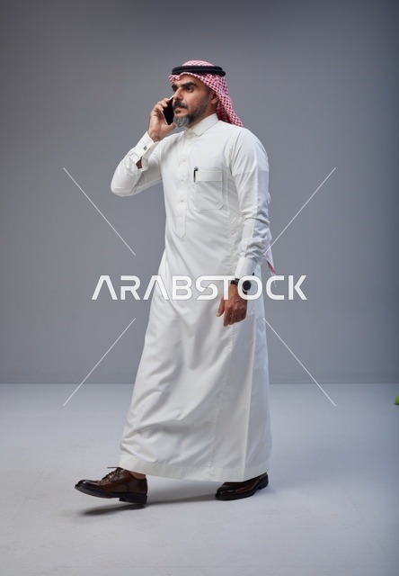 رجل سعودي بالزي التقليدي يتحدث عبر الهاتف الجوال