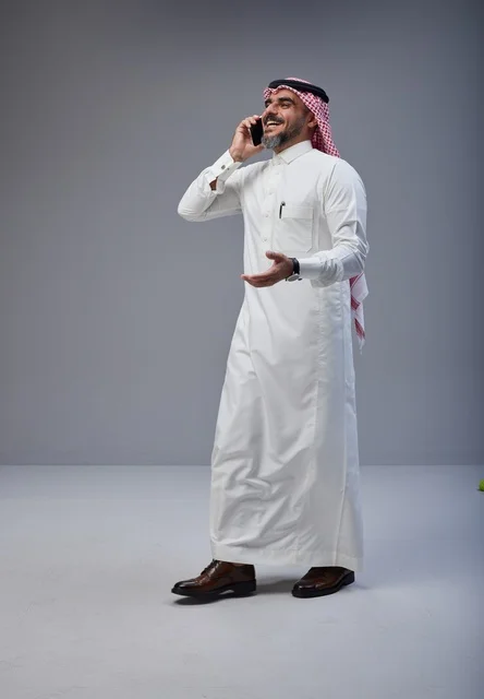 رجل سعودي بالزي التقليدي يتحدث عبر الهاتف الذكي