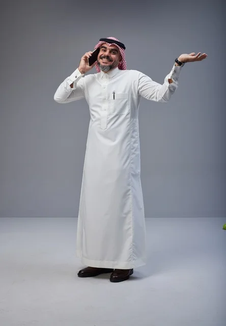 Saudi Man in Traditional Thobe Talking on Smartphone