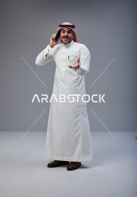 Saudi Man in Traditional Thobe Talking on Smartphone