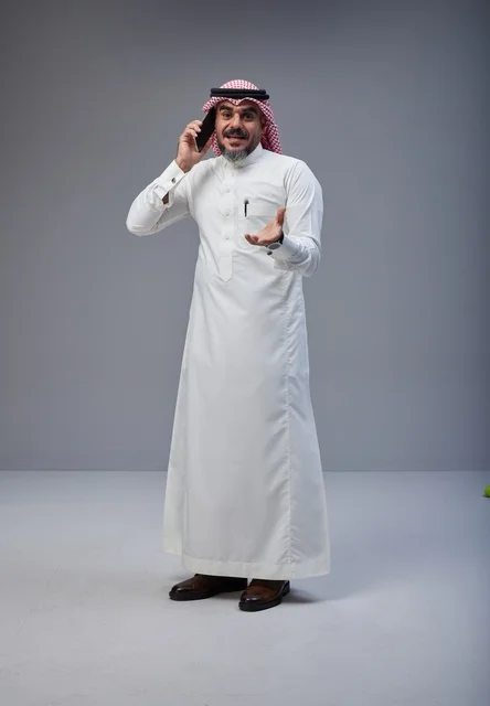 Saudi Man in Traditional Thobe Talking on Smartphone