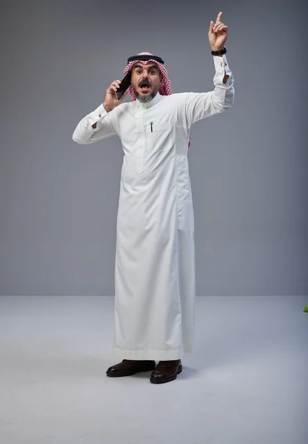 Saudi Man in Traditional Dress Talking on Smartphone